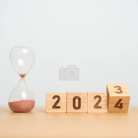 Photo for Flipping block 2023 to 2024 text with hourglass on table. Resolution, time, plan, goal, motivation, reboot, countdown  and New Year holiday concepts - Royalty Free Image