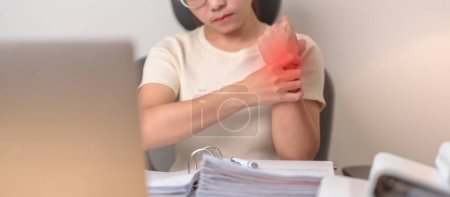 Frau, die Schmerzen am Handgelenk hat, wenn sie Laptop und Maus benutzt, während sie lange am Arbeitsplatz arbeitet. Sehnenscheidenentzündung, Rheuma, Karpaltunnelsyndrom oder Office-Syndrom