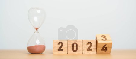 Photo for Flipping block 2023 to 2024 text with hourglass on table. Resolution, time, plan, goal, motivation, reboot, countdown  and New Year holiday concepts - Royalty Free Image