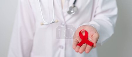 Foto de Médico con cinta roja para el Día Mundial del SIDA de diciembre, síndrome de inmunodeficiencia adquirida, mes de conciencia del cáncer del mieloma múltiple y semana nacional de la cinta roja. Salud y concepto del día mundial del cáncer - Imagen libre de derechos