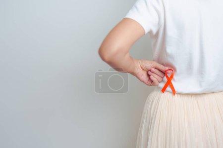 Foto de Mujer con dolor de espalda en el abdomen con cinta naranja. Conciencia del cáncer de riñón mes de marzo, enfermedad del sistema urinario y piedras, cáncer, riñón crónico, urología, concepto renal y trasplante - Imagen libre de derechos