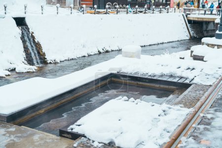 Téléchargez les photos : Bain de pieds source chaude à Ginzan Onsen avec chute de neige en hiver est la plus célèbre source chaude japonaise à Yamagata, Japon. - en image libre de droit