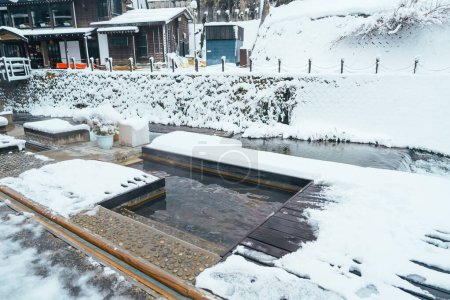 Téléchargez les photos : Bain de pieds source chaude à Ginzan Onsen avec chute de neige en hiver est la plus célèbre source chaude japonaise à Yamagata, Japon. - en image libre de droit