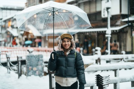 Téléchargez les photos : Femme touriste Visiter Ginzan Onsen à Yamagata, heureux Voyageur visiter le village japonais Onsen avec de la neige en saison hivernale. repère et populaire pour l'attraction au Japon. Voyage et vacances concept - en image libre de droit
