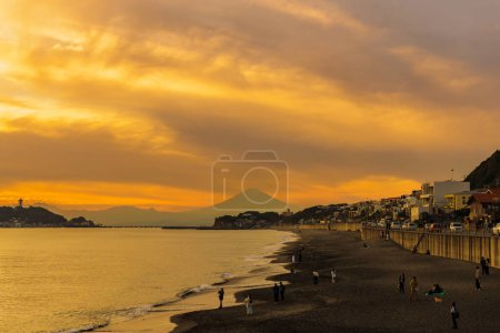 Téléchargez les photos : Paysage Kamakura Yuigahama Beach avec la ville de Kamakura et la montagne Fujisan. Silhouette crépusculaire Mont Fuji derrière l'île d'Enoshima à Kamakura, Kanagawa, Japon. Point de repère pour l'attraction touristique près de tokyo - en image libre de droit