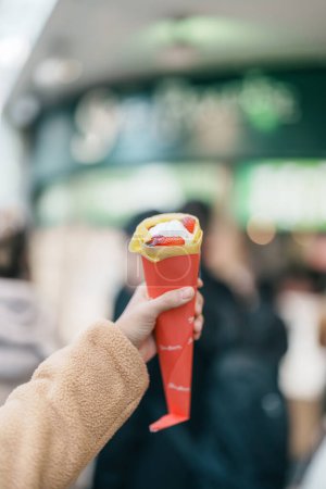 Téléchargez les photos : Femme main tenant des crêpes aux fraises. Crêpes à dessert populaires au Japon - en image libre de droit
