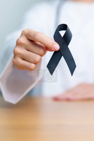 Photo for Melanoma and skin cancer, Vaccine injury awareness month and rest in peace concepts. doctor holding black Ribbon - Royalty Free Image
