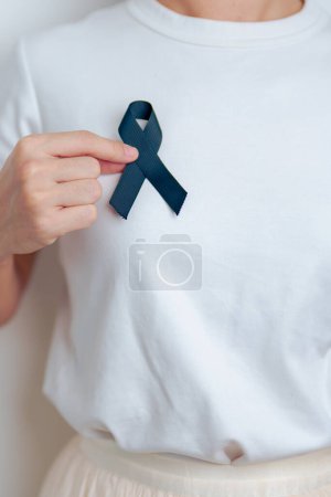 Melanoma y cáncer de piel, mes de concientización de lesiones vacunales y descanso en conceptos de paz. Mujer sosteniendo cinta negra