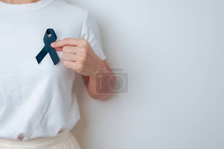 Téléchargez les photos : Mélanome et cancer de la peau, Mois de sensibilisation aux blessures causées par le vaccin et concept de paix. Femme tenant ruban noir - en image libre de droit
