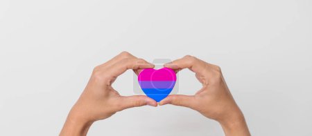 Bisexualität Feiern Sie den Tag und LGBT Stolz Monat, LGBTQ + oder LGBTQIA + Konzept. Hand hält lila, rosa und blaue Herzform für Lesben, Schwule, Bisexuelle, Transgender, Queer und Pansexuelle