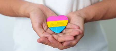 Pansexual Pride Day and LGBT pride month concept. hand holding pink, yellow and blue heart shape for Lesbian, Gay, Bisexual, Transgender, Queer and Pansexual community