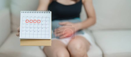 Photo for Menstruation period cycle of monthly and Stomachache concepts. woman having abdomen pain with hot water bottle and calendar, illness female suffer from premenstrual ache and body Health problem - Royalty Free Image