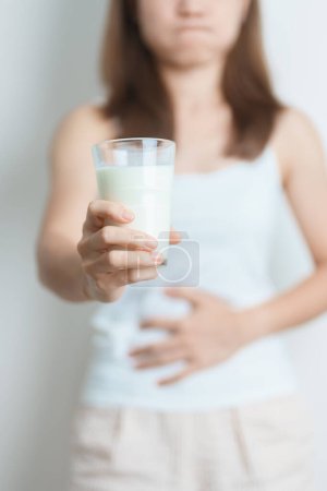 Intolerancia a la lactosa y alergia a la leche. mujer sostener vaso de leche y tener calambres abdominales y dolor cuando beber leche de vaca. Dolor de estómago, intolerante a los lácteos, Náuseas, distensión abdominal, gases y diarrea