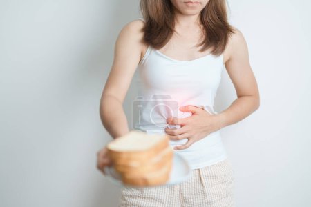 Photo for Gluten intolerance, Gluten free and celiac disease or wheat allergy concept. woman hold Bread and having abdominal pain after eat gluten. stomach ache, Nausea, Bloating, Gas, Diarrhea and Skin rash - Royalty Free Image