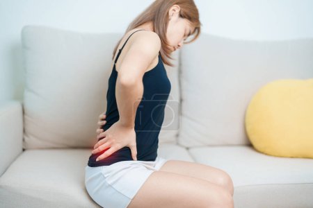 Frau, die zu Hause Rückenschmerzen hat. erwachsene Hündin mit Muskelschmerzen aufgrund von Piriformis-Syndrom, Rückenschmerzen und Wirbelsäulenkompression. Bürosyndrom und medizinisches Konzept