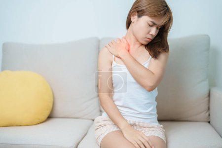 Frau mit Schulter- und Nackenschmerzen zu Hause. Muskelschmerzen aufgrund des Myofaszialen Schmerzsyndroms und der Fibromyalgie, Rheuma, Skapulierschmerzen, Halswirbelsäule. Ergonomisches Konzept