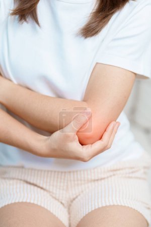 Woman having elbow ache at home, muscle pain due to lateral epicondylitis or tennis elbow. injury, Health and medical concept