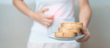 Glutenunverträglichkeit, glutenfreie und Zöliakie oder Weizenallergie. Frau hält Brot und hat Bauchschmerzen, nachdem sie Gluten gegessen hat. Magenschmerzen, Übelkeit, Blähungen, Gas, Durchfall und Hautausschlag