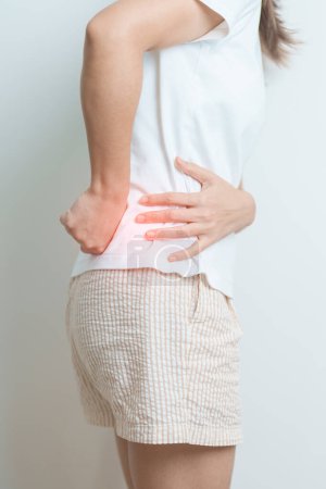 Frau, die zu Hause Rückenschmerzen hat. erwachsene Hündin mit Muskelschmerzen aufgrund von Piriformis-Syndrom, Rückenschmerzen und Wirbelsäulenkompression. Bürosyndrom und medizinisches Konzept