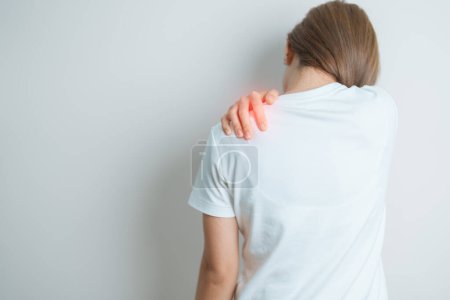 Frau mit Schulter- und Nackenschmerzen zu Hause. Muskelschmerzen aufgrund des Myofaszialen Schmerzsyndroms und der Fibromyalgie, Rheuma, Skapulierschmerzen, Halswirbelsäule. Ergonomisches Konzept