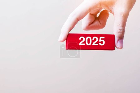 Geschäftsmann hält Holzblock 2025 in der Hand. Auflösung, Strategie, Lösung, Ziel, Risikogeschäft und Neujahrskonzepte