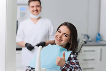Foto de Mujer joven feliz y dentista masculino después del tratamiento en la clínica - Imagen libre de derechos