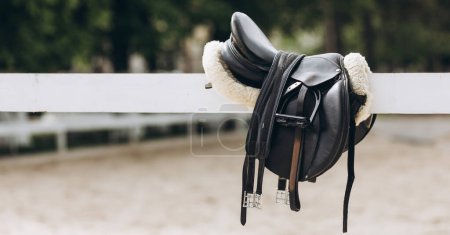 Foto de English saddle hanging on a wooden stable door - Imagen libre de derechos