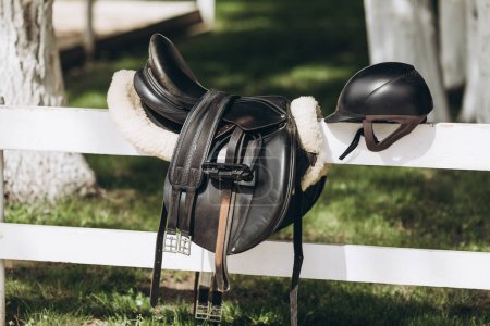 Foto de English saddle hanging on a wooden stable door - Imagen libre de derechos