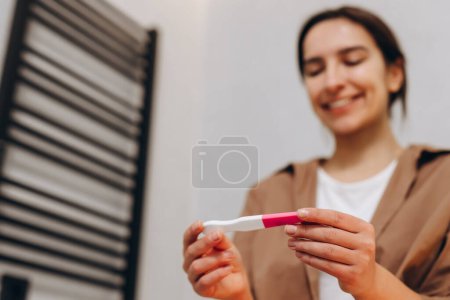Foto de A happy young girl saw the coveted two stripes on the pregnancy test. Happy pregnant woman. - Imagen libre de derechos