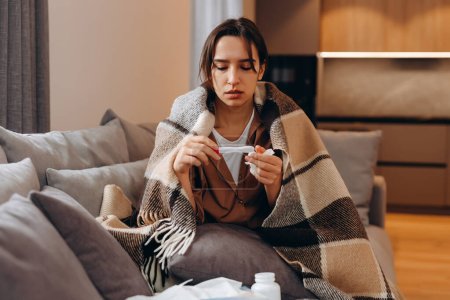Ungesunde Frauen, die in Decken sitzen, fühlen sich krank und leiden an Grippe oder dem Covid-19-Coronavirus. Ungesunde junge Nieserinnen haben laufende Nase, kämpfen zu Hause mit Grippe oder Erkältung.