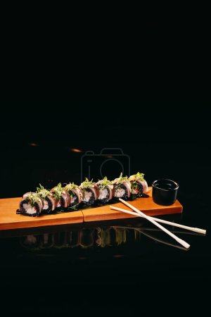 Photo for Salmon Dragon sushi on a wooden board with Chinese chopsticks and say sause - Royalty Free Image