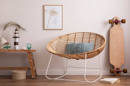 Téléchargez les photos : Interior design of cozy and summer living room with rattan armchair, couch, pillows, mock u poster frame, side table, bamboo longboard, decoration, carpet and personal accessories. Stylish home decor. - en image libre de droit