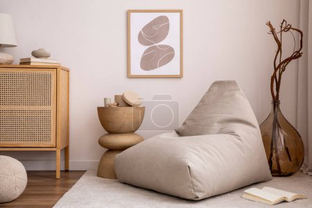Photo for Domestic and cozy interior of living room with mock up poster frame, beige carpet, design pouf, lamp, decoration, wooden side table and beige accessories. Creative home decor. Template. - Royalty Free Image