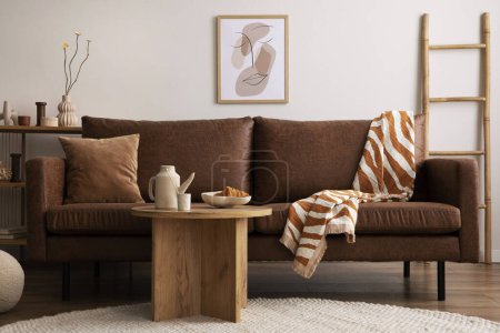 Foto de Warm and cozy interior of living room space with brown sofa, round beige carpet, wooden coffee table, mock up poster frames, decoration and elegant personal accessories. Cozy home decor. Template. - Imagen libre de derechos