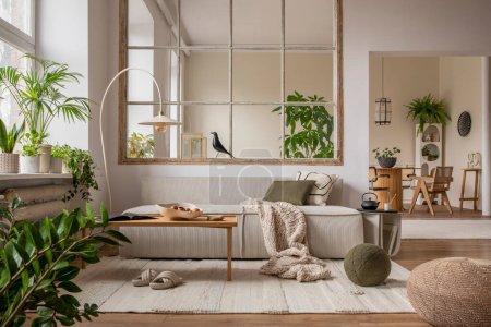 Téléchargez les photos : Open space interior with modular sofa, wooden coffee table, big window, patterned pillows, braided plaid, stylish lamp, wooden coffee table, plants and personal accessories. Home decor. Template. - en image libre de droit