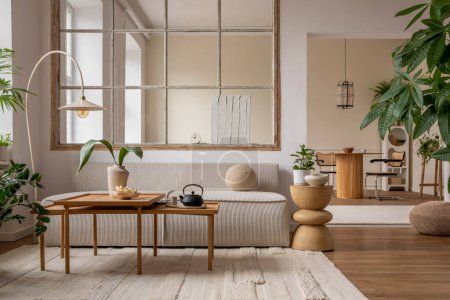Téléchargez les photos : Open space interior with modular sofa, wooden coffee table, big window, beige rug, round pillow, stylish table, lamp, plants, vase with leaves and personal accessories. Home decor. Template. - en image libre de droit