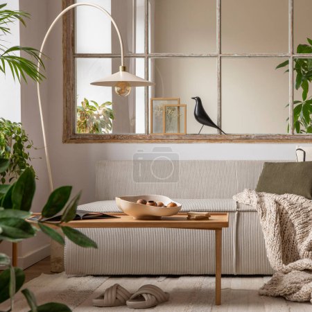 Téléchargez les photos : Open space interior with modular sofa, wooden coffee table, big window, patterned pillows, braided plaid, stylish lamp, wooden coffee table, plants and personal accessories. Home decor. Template. - en image libre de droit