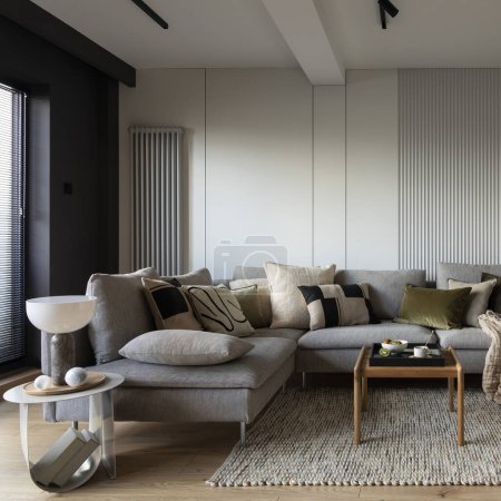 Creative composition of living room interior with design gray sofa, wooden coffee table, stylish carpet, beige side table, pillows, personal accessories and big tv. Stylish home decor. Template.
