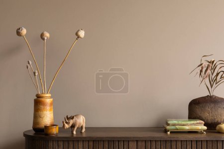 Photo for Creative composition of living room interior with wooden sideboard, stylish vase with dried flowers, stylish casket, nuts in bowl, brown wall and personal accessories. Home decor. Template. - Royalty Free Image