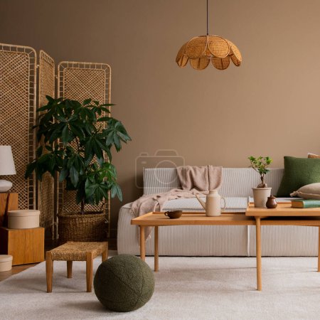 Interior design of living room with modular  sofa, wooden coffee table, rattan sideboard, green pillow, lamp, brown pouf, beige rug, plants and personal accessories. Home decor. Template. 