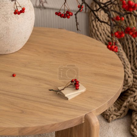 Photo for Minimalist composition of japandi living room interior with round wooden coffee table, stylish vase with rowan, simple beige carpet, braided plaid and personal accessories. Home decor. Template. - Royalty Free Image
