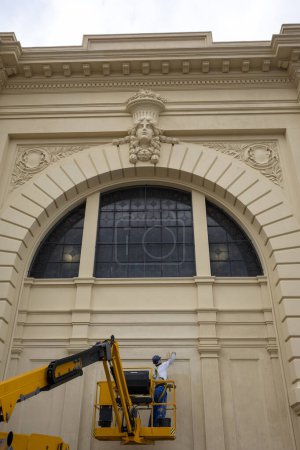 Foto de Worker performs maintenance and repairs on the painting of the external wall of the Municipal Market in Sao Paulo, Brazil - Imagen libre de derechos