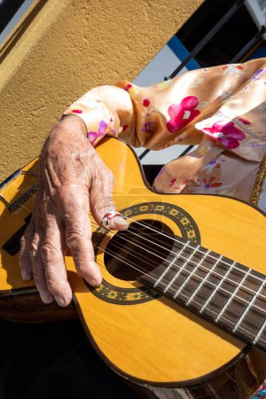 Foto de Detail of a gentleman playing the guitar during the Folia de Reis folk festival. Sunny day; colorful clothes - Imagen libre de derechos