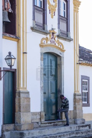 Photo for Sao Joao de Rey, Minas Gerais, Brazil - Jul13, 2023 - man prays in front of the baroque chapel of Santo Antonio in the historic center of Sao Joao del Rei in the state of Minas Gerais, Brazil - Royalty Free Image