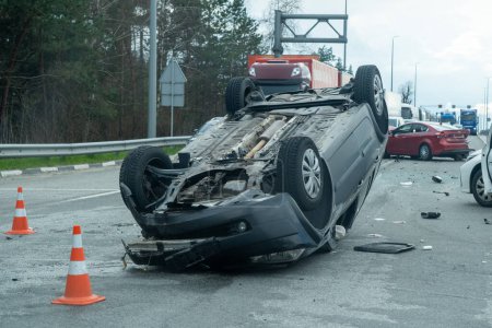 Kyiv region, Ukraine - April 10, 2023: Overturned car on the highway during the approach to the city. Traffic accident on the autobahn. Crashed and overturned cars on the highway. 