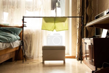 Photo for Dry the shorts on the photo gate above the convector in the apartment, dry the washed things in the apartment, warm house and heating - Royalty Free Image