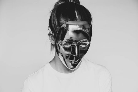 Foto de Una chica con una máscara de plástico sin rostro inclinó la cabeza sobre un fondo blanco foto en blanco y negro, anonimato, misterio - Imagen libre de derechos