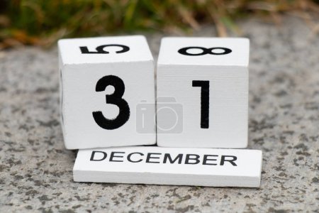 December 31 is written on wooden calendar cubes which lies on a gray stone on the street, Happy New Year, holiday