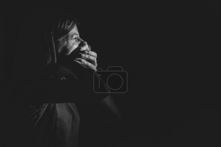 Photo for The girl closes her mouth with her hands in the dark, you can't say, be silent - Royalty Free Image