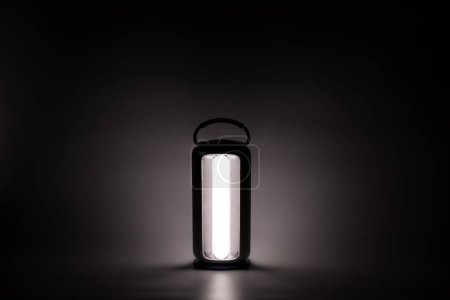 Handheld-LED-Lampe leuchtet im Dunkeln auf weißem Hintergrund, Licht und Schatten